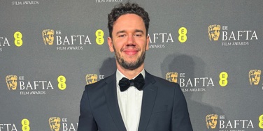 Marcin Mazurek at 2025 BAFTAs, in front of BAFTA backdrop and holding award