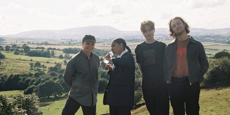 Four-piece band English Teacher stood in a line in countryside setting