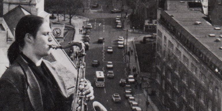 Person playing a saxophone, leeds in the background